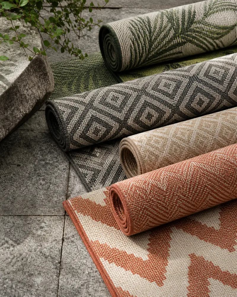 Outdoor rugs layered in warm mineral and terracotta tones